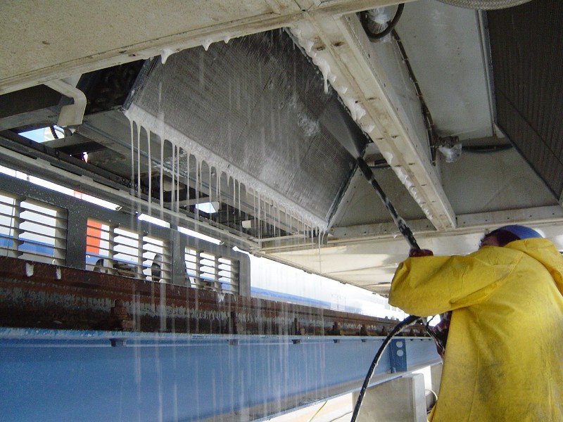 Picture of a technician with a commercial jet washer going through a deep cleaning process as part of HVAC Corrosion Protection and Refurbishment